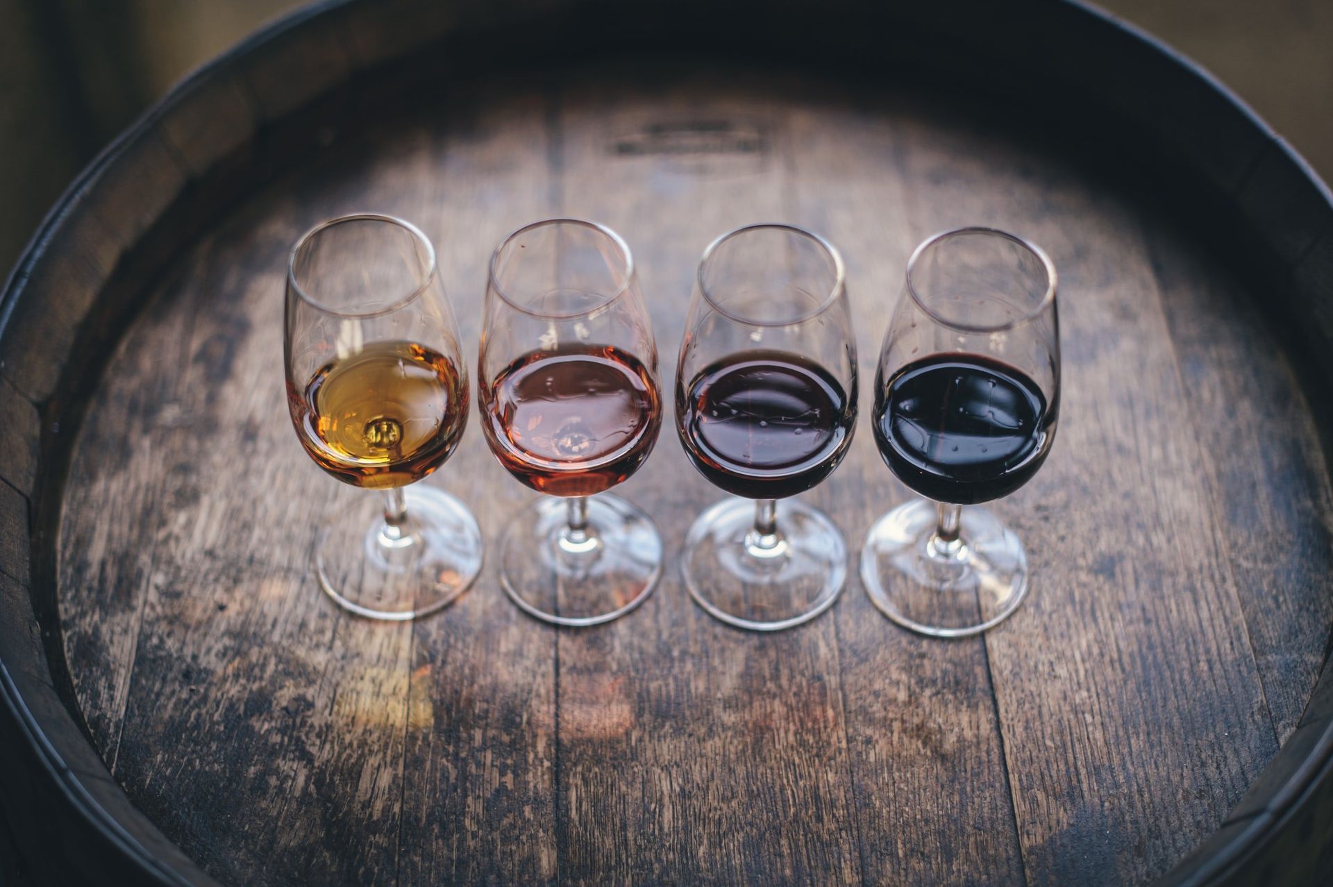 Four glasses of wine are sitting on top of a wooden barrel.