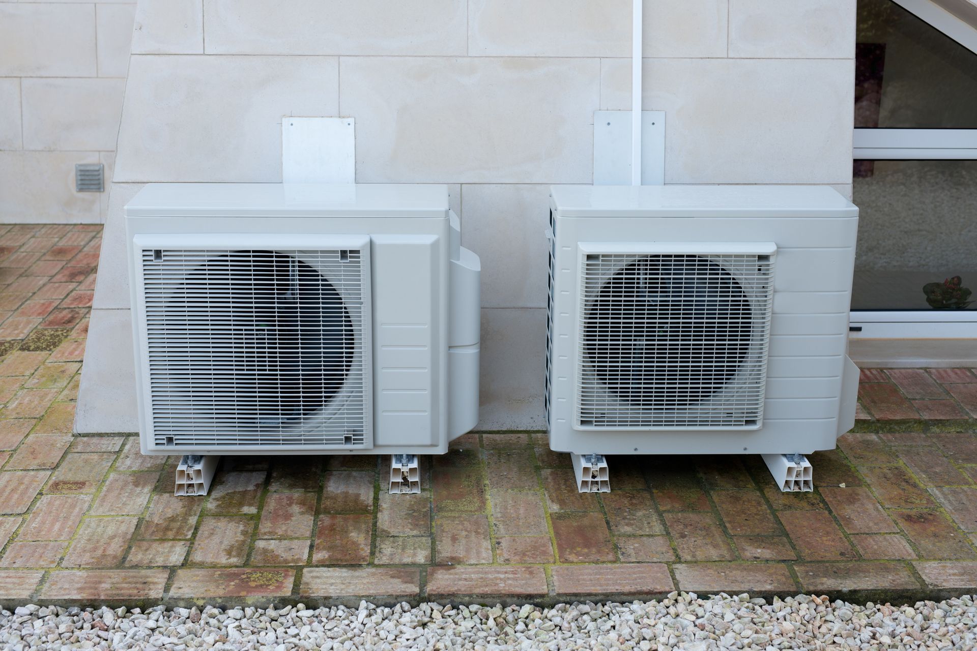 Two white air conditioners are next to each other on a brick sidewalk  — Phoenix, AZ — Trutek Air Conditioning and Heating LLC