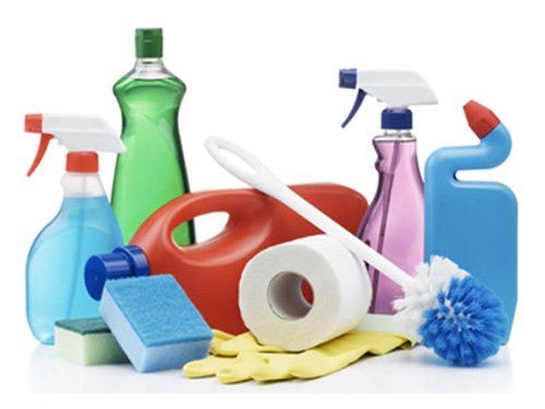 Various cleaning bottles in different colors with two sponges, roll of toilet roll and a toilet brush