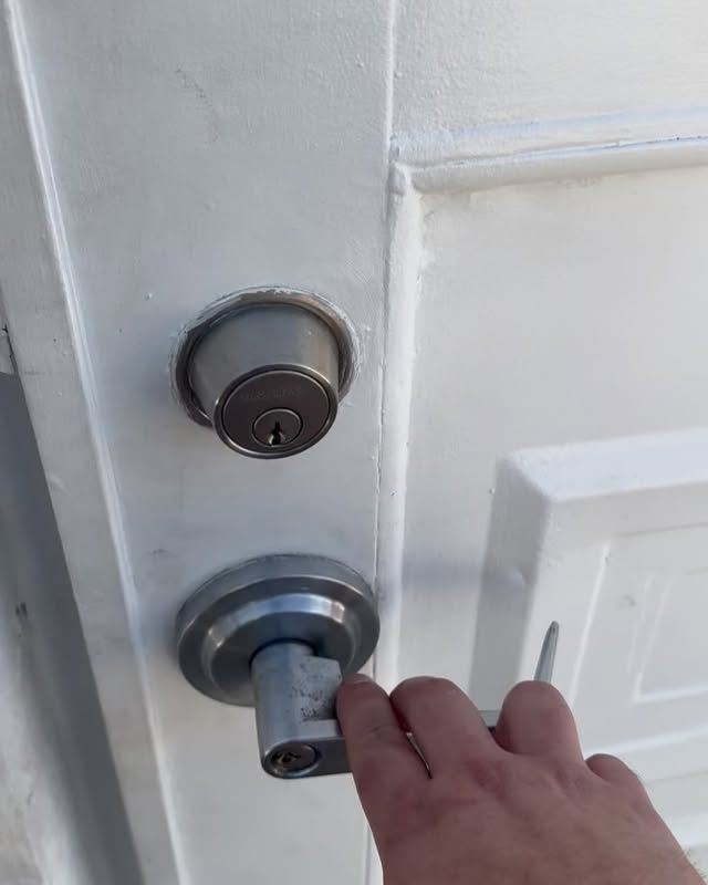A person is opening a white door with a key.