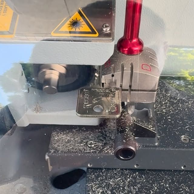 A key is being cut in a machine that has the letter d on it