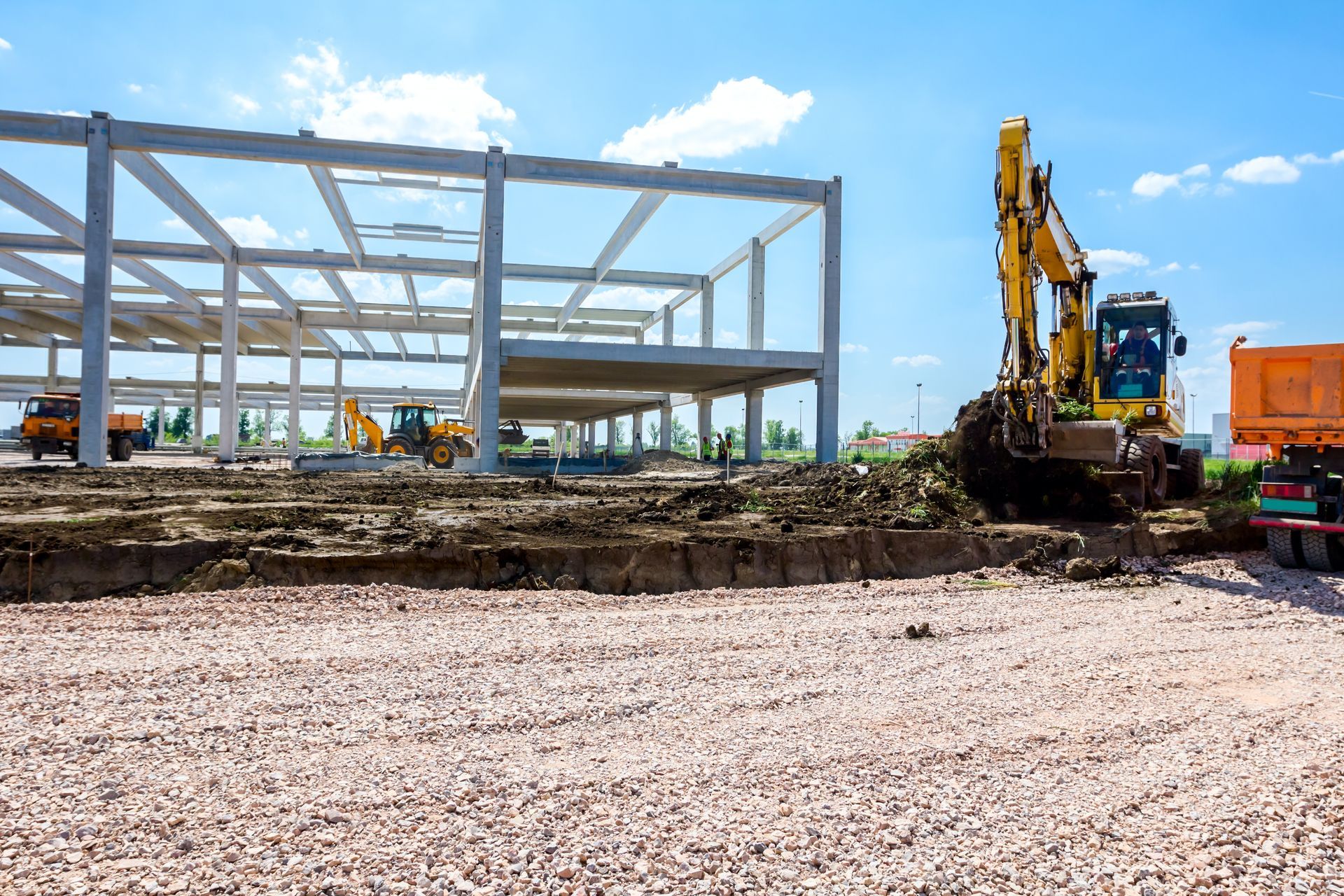 Backhoe transferring soil into a truck at a construction site.