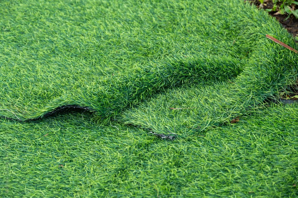 a piece of artificial green grass is laying on the ground