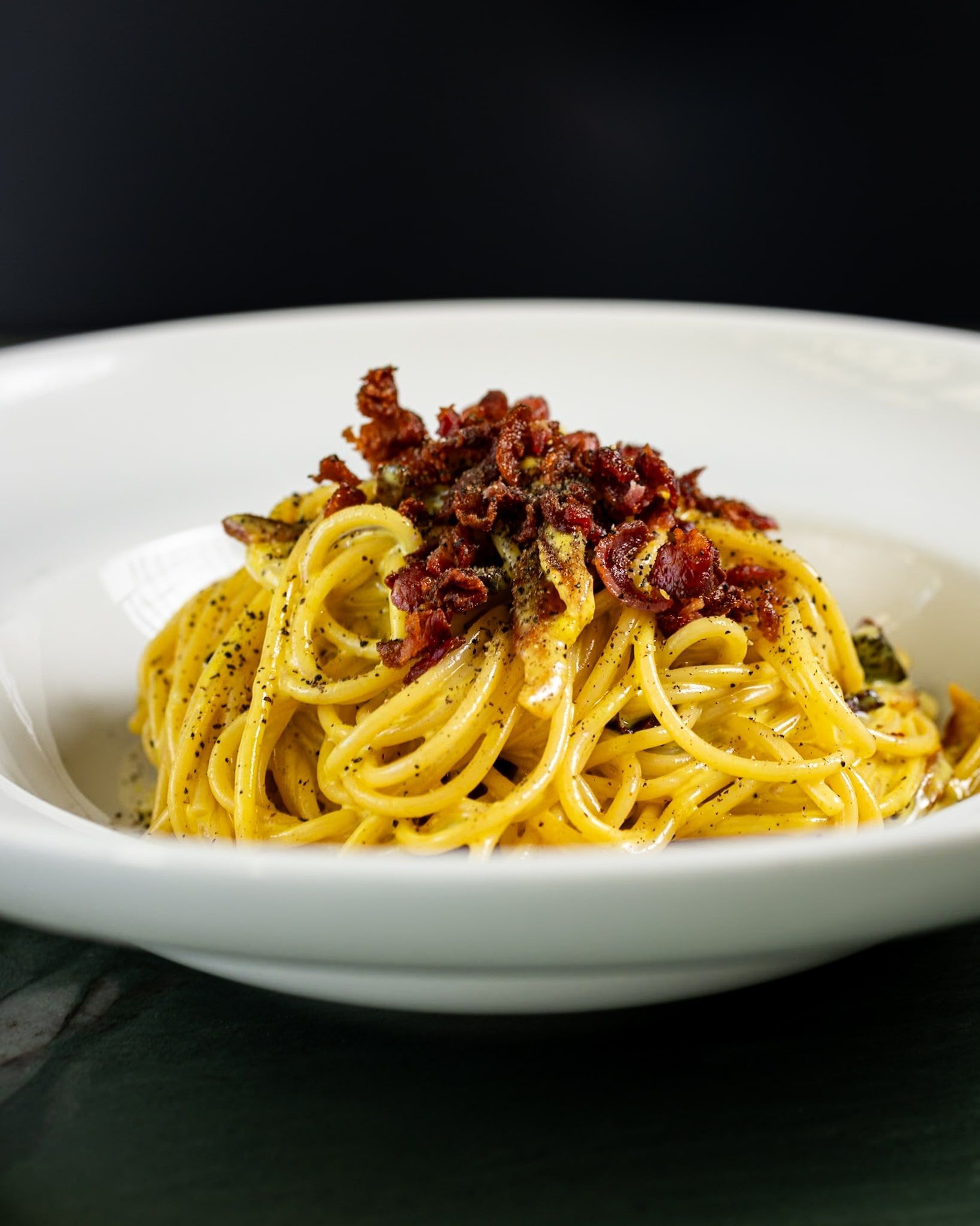 A white bowl filled with spaghetti and meat on a table.