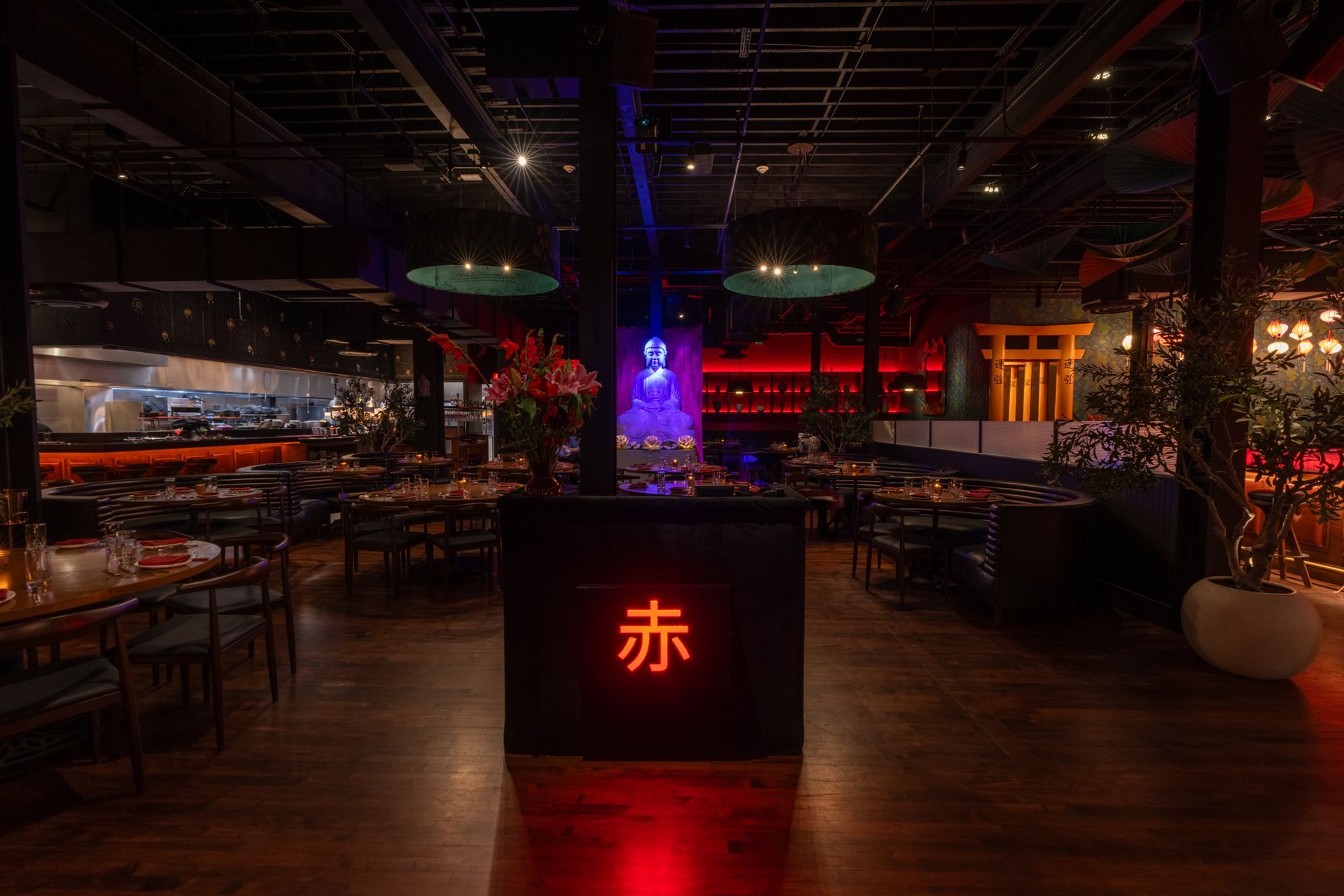 A restaurant with a lot of tables and chairs and a red sign in the middle of the room.