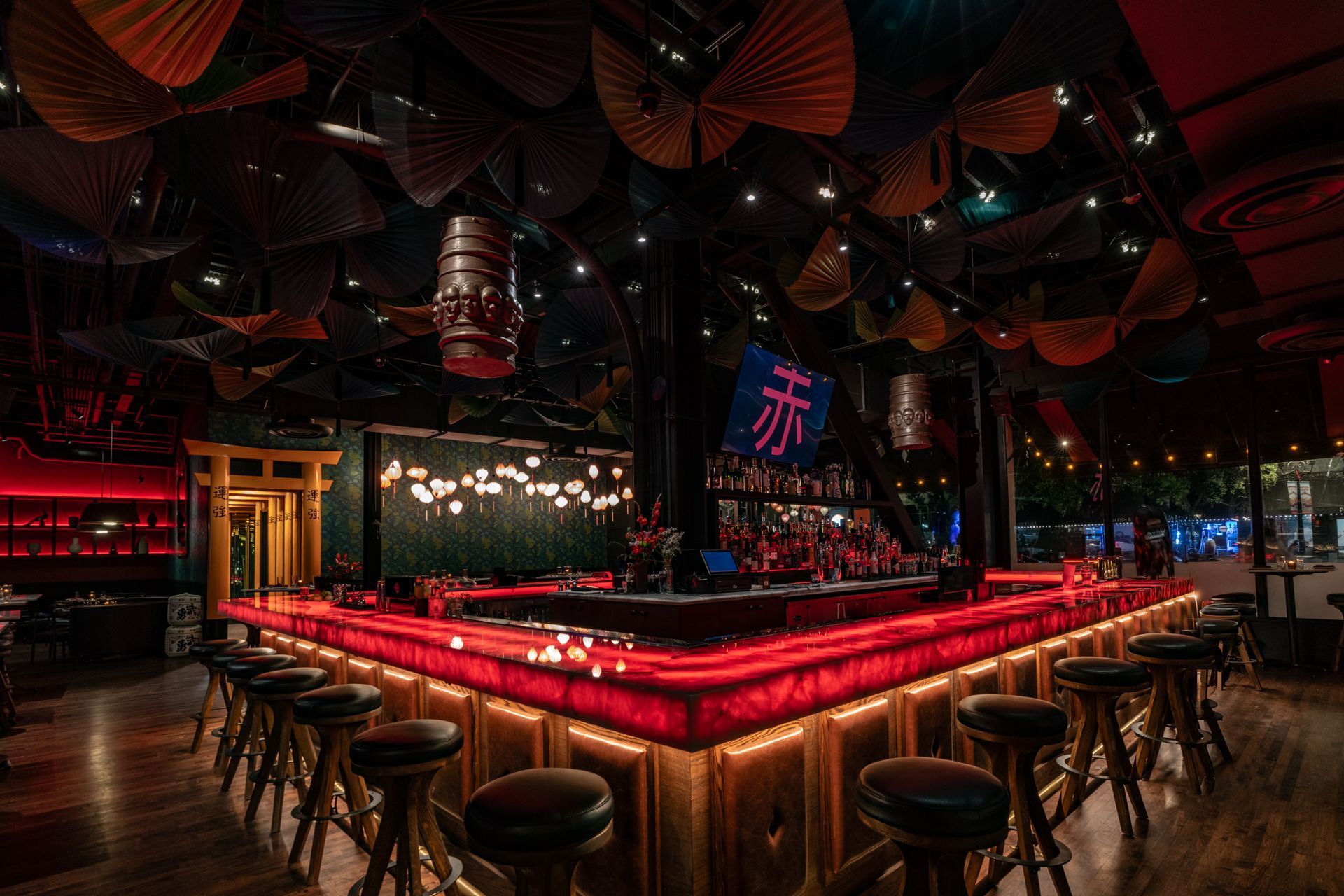 A restaurant with a long red bar and stools.
