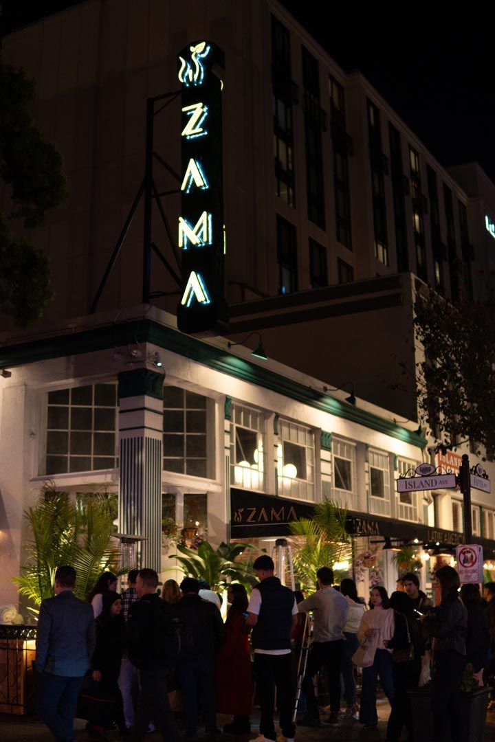 A group of people are standing outside of a building with a sign that says ' n2a mi ' on it