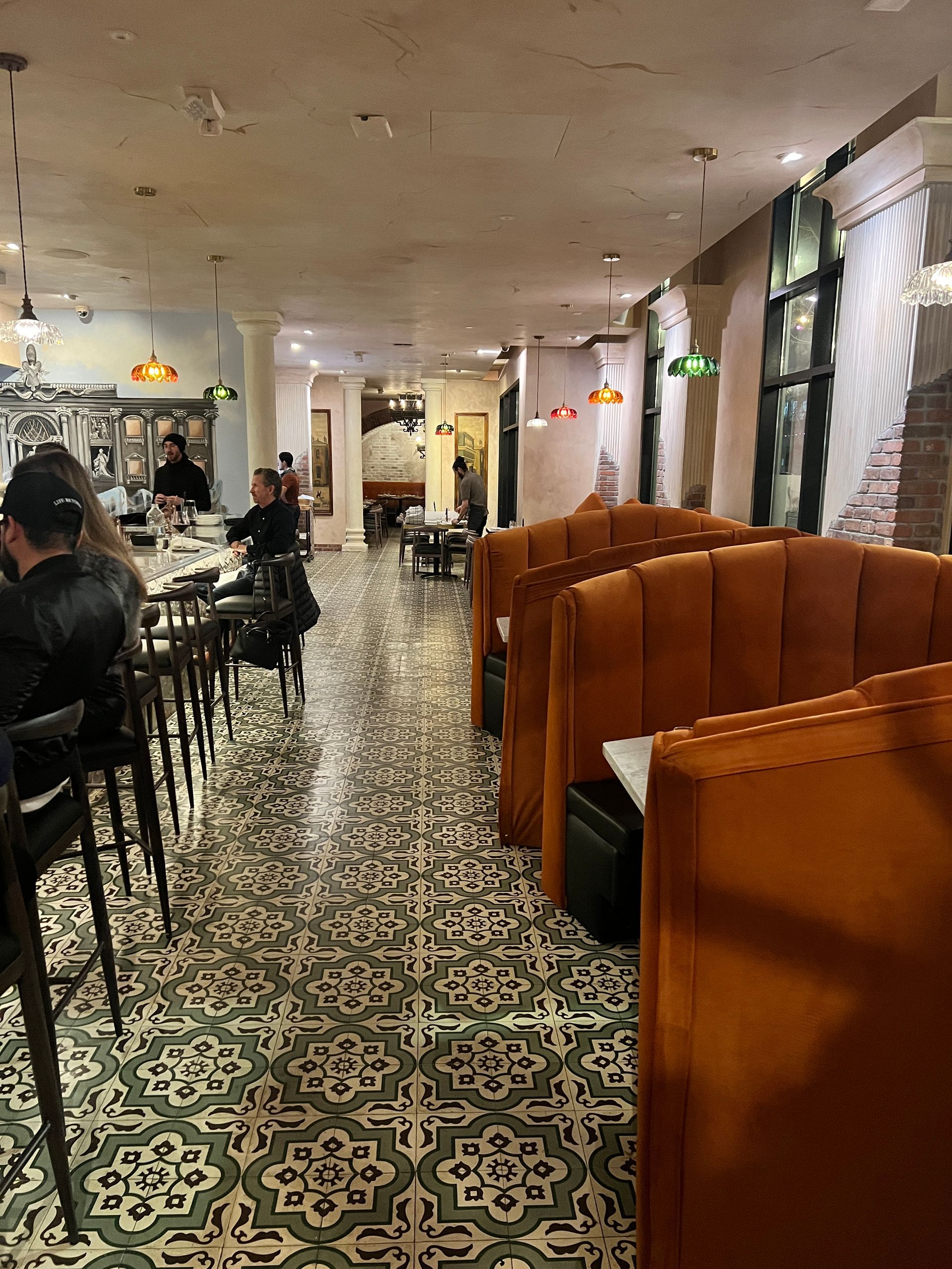 People are sitting at tables in a restaurant with a tiled floor.