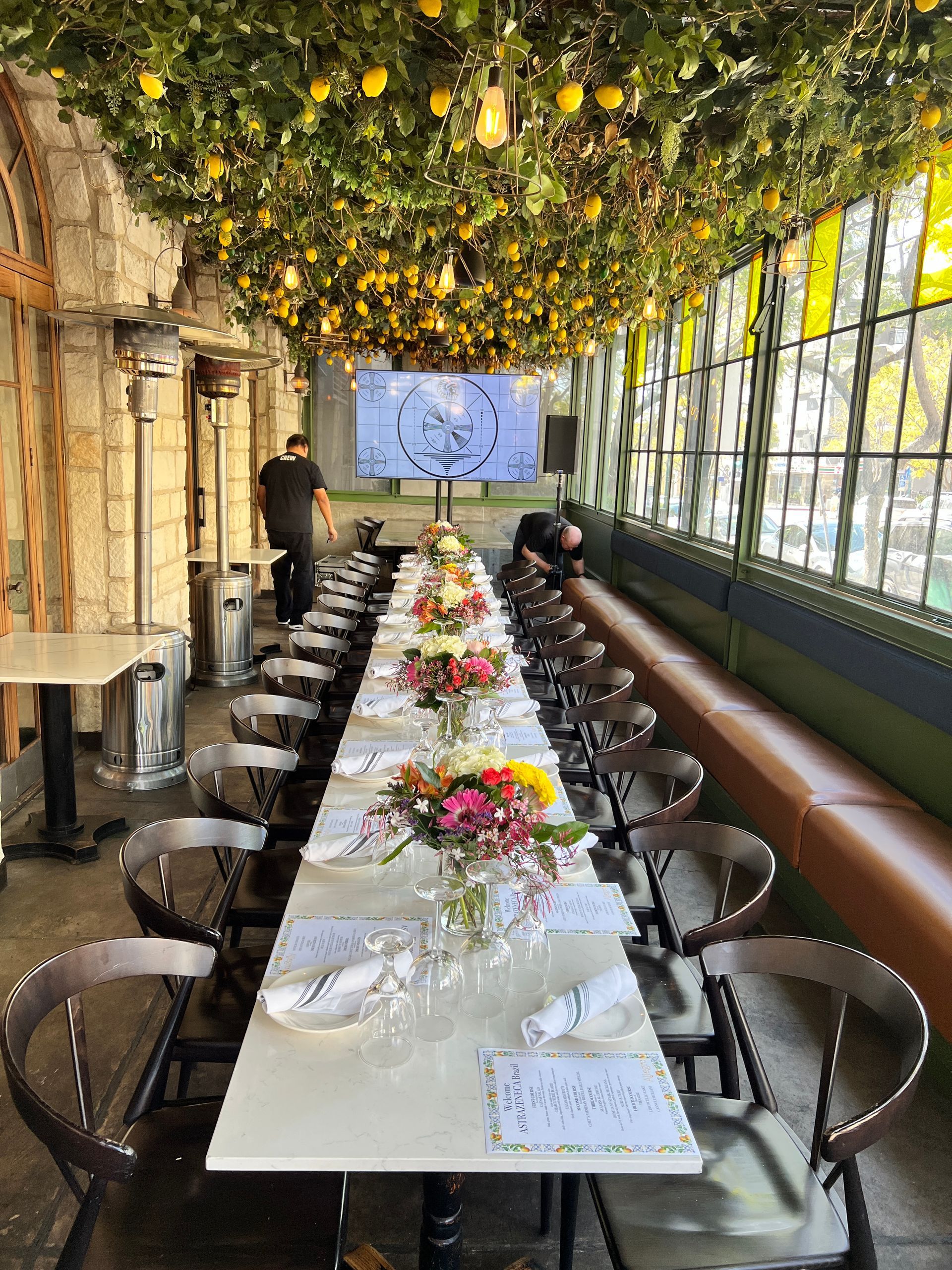 A long table with flowers on it in a restaurant.