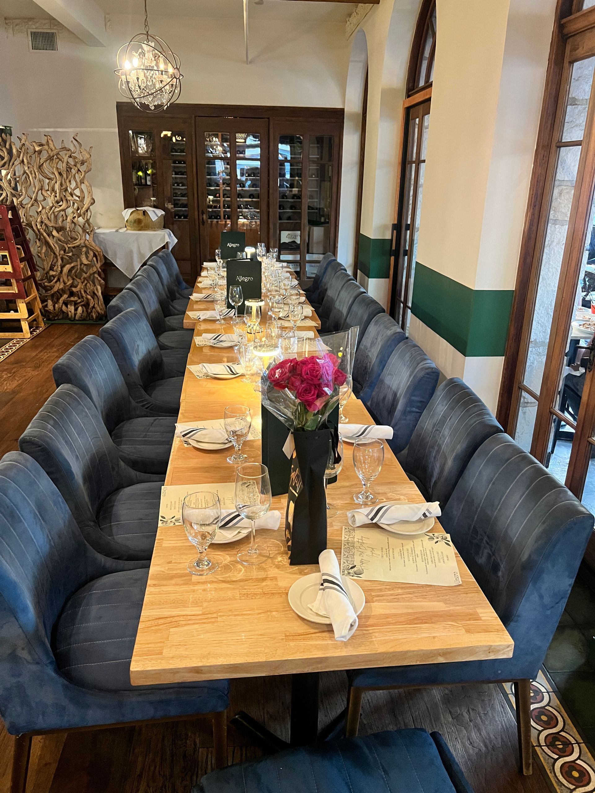 A long table with a vase of flowers on it in a restaurant.