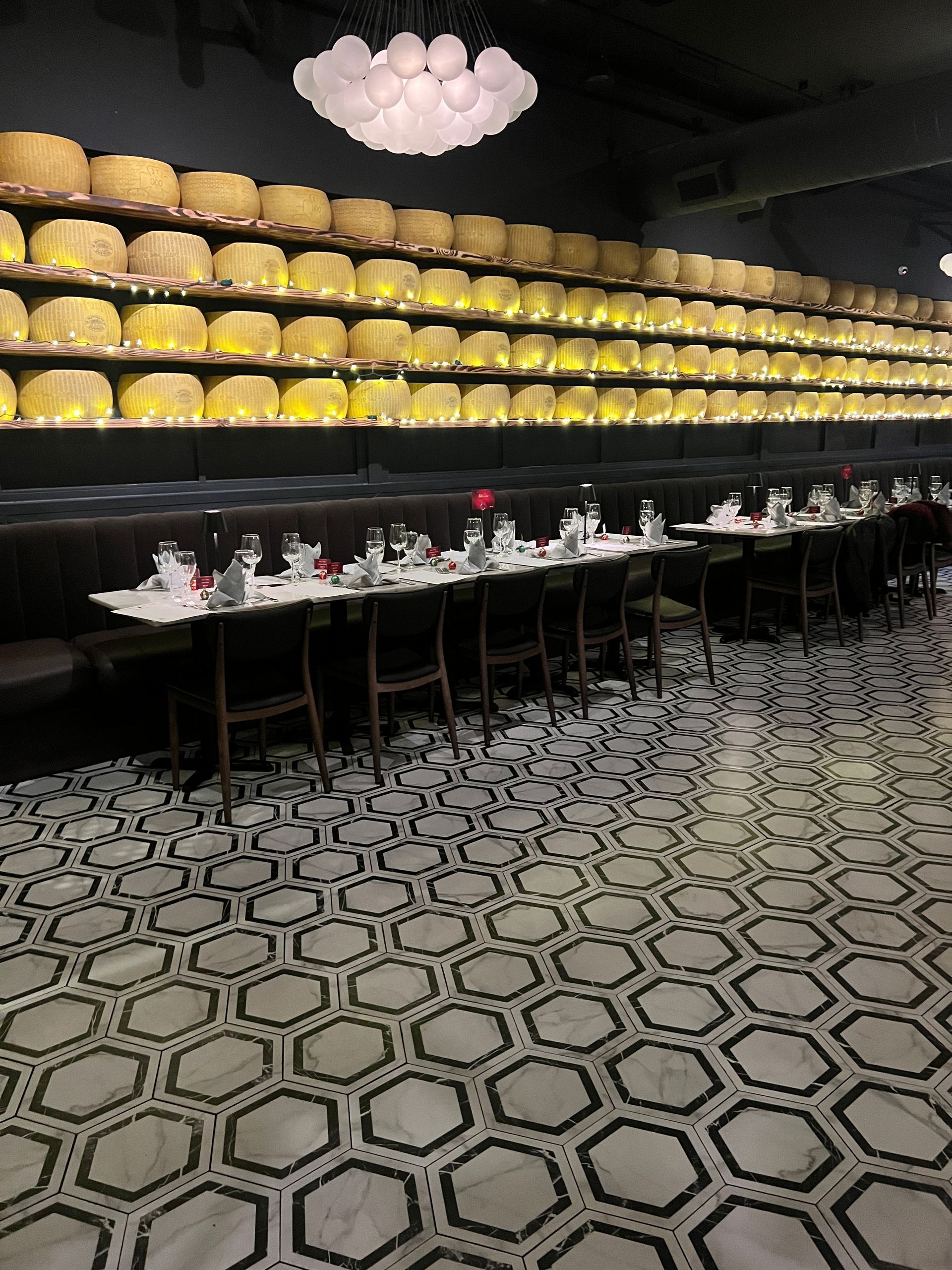 A restaurant with tables and chairs and a wall of cheese