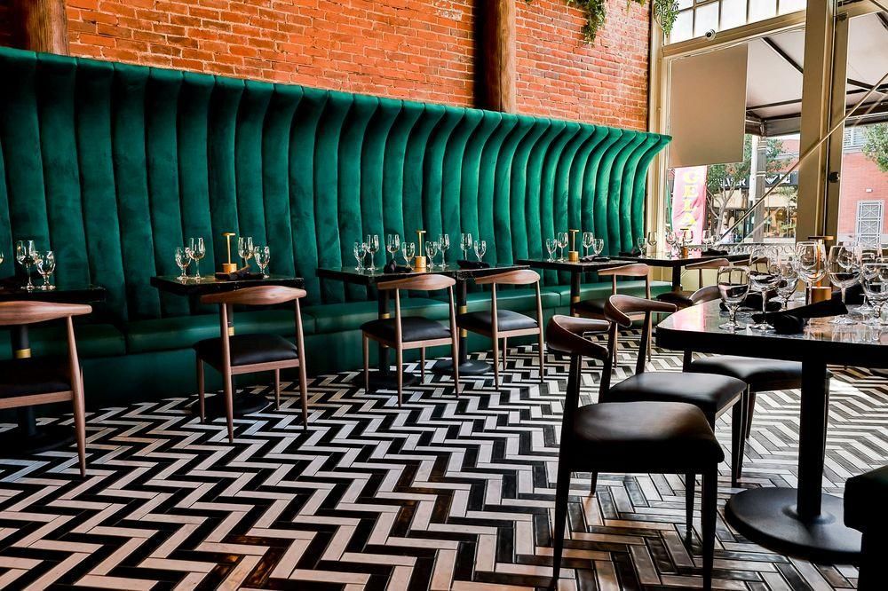 A restaurant with tables and chairs and a black and white chevron floor.