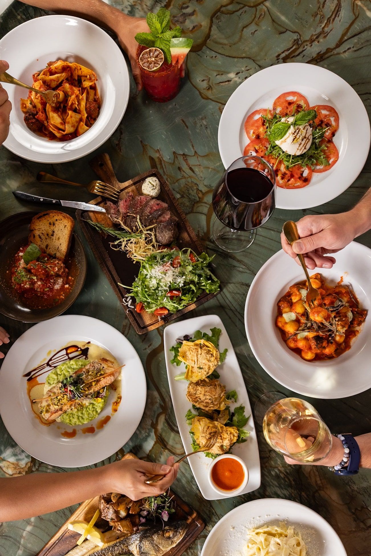 A table topped with plates of food and glasses of wine.
