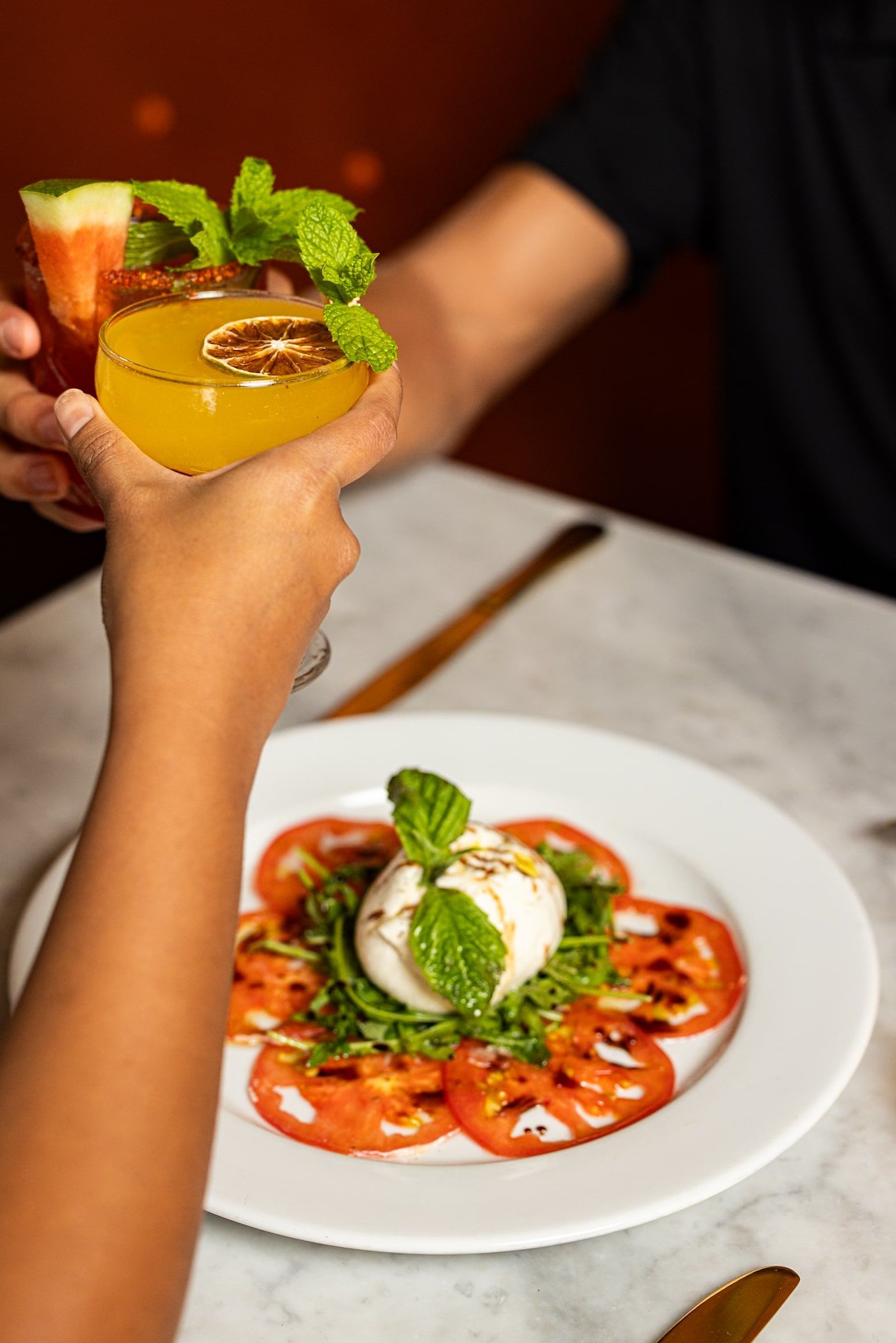 A person is holding a drink in front of a plate of food.