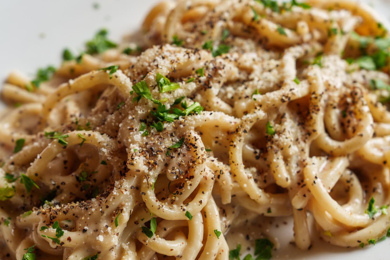 A close up of a plate of pasta with sauce and parsley on a table.