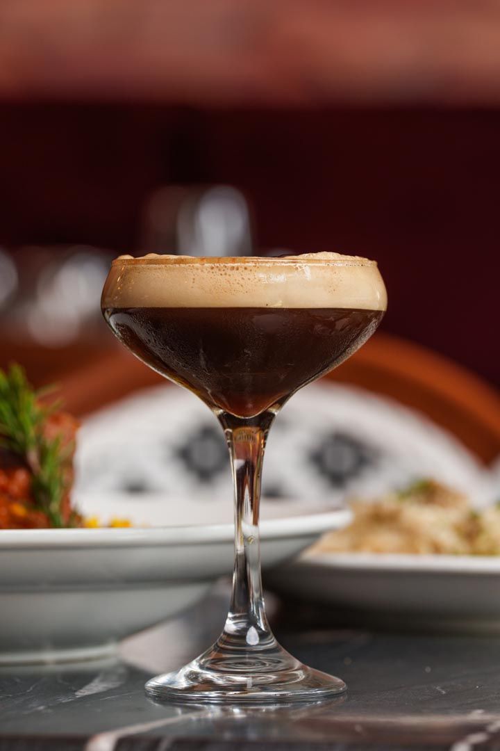 A close up of a martini glass filled with a drink on a table.