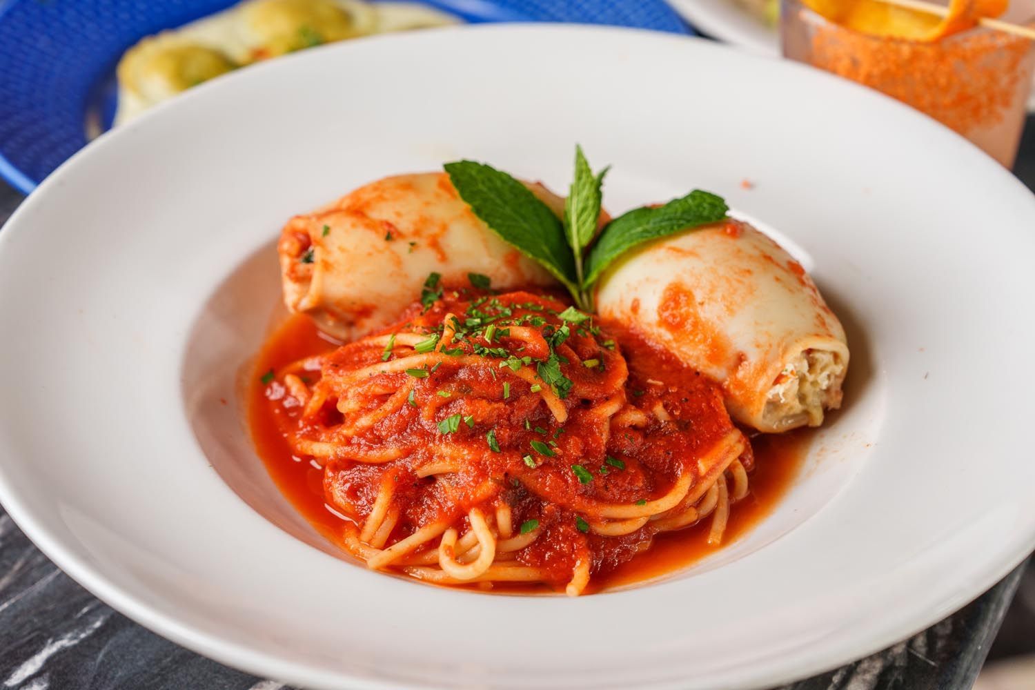 A white plate topped with spaghetti and squid in tomato sauce.