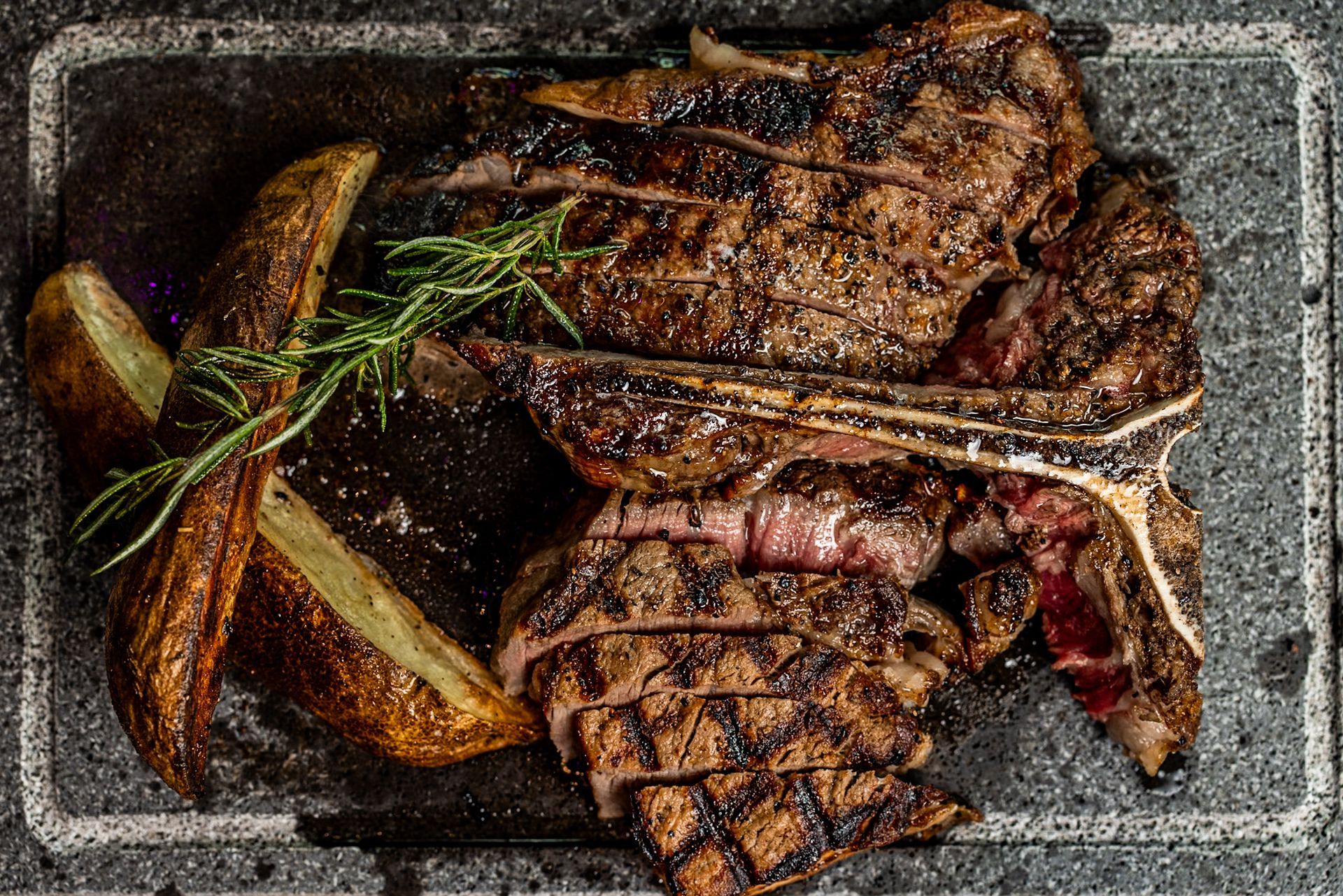 A close up of a steak and potatoes on a plate.