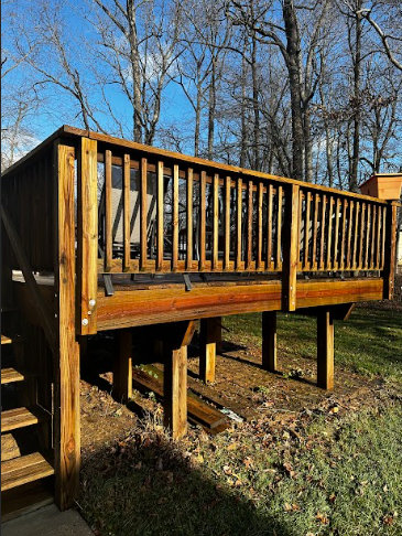 A wooden deck with stairs leading up to it and trees in the background.