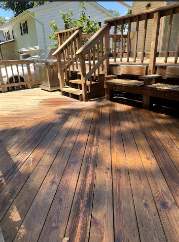 A wooden deck with stairs and a house in the background.