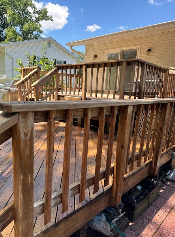 A wooden deck with stairs leading up to it and a house in the background.