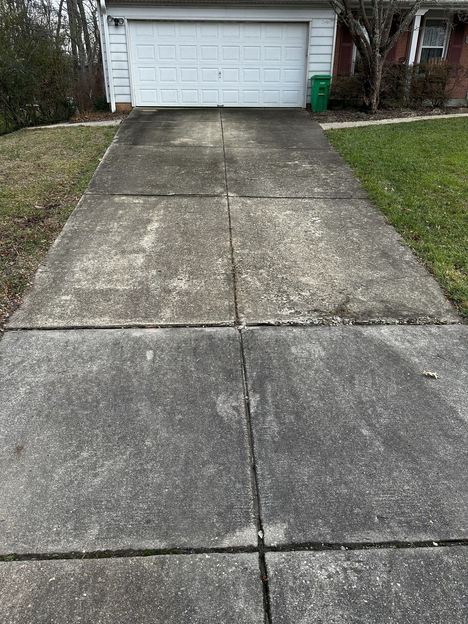A dirty concrete driveway leading to a garage door.