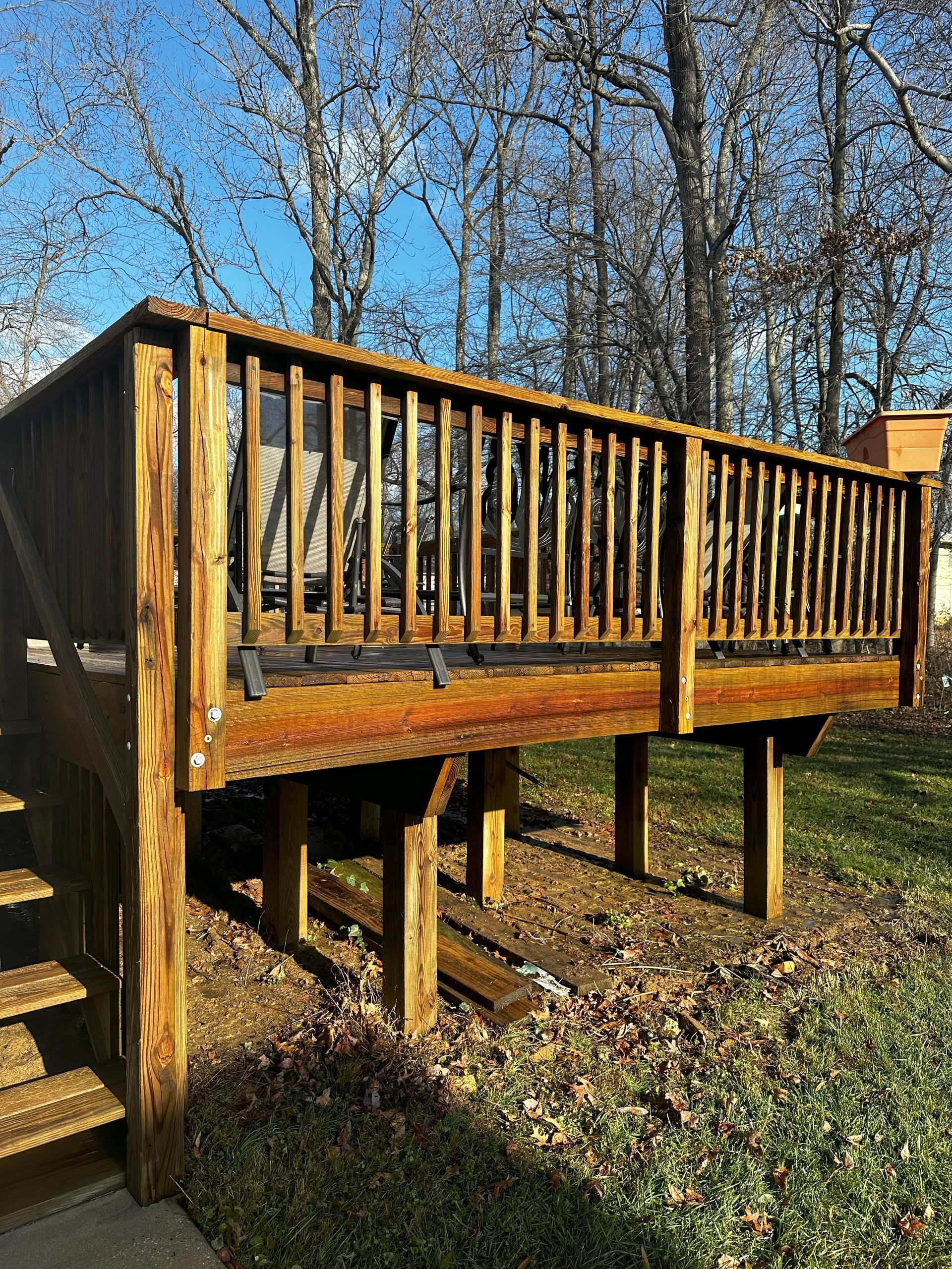 A wooden deck with stairs leading up to it in a yard.