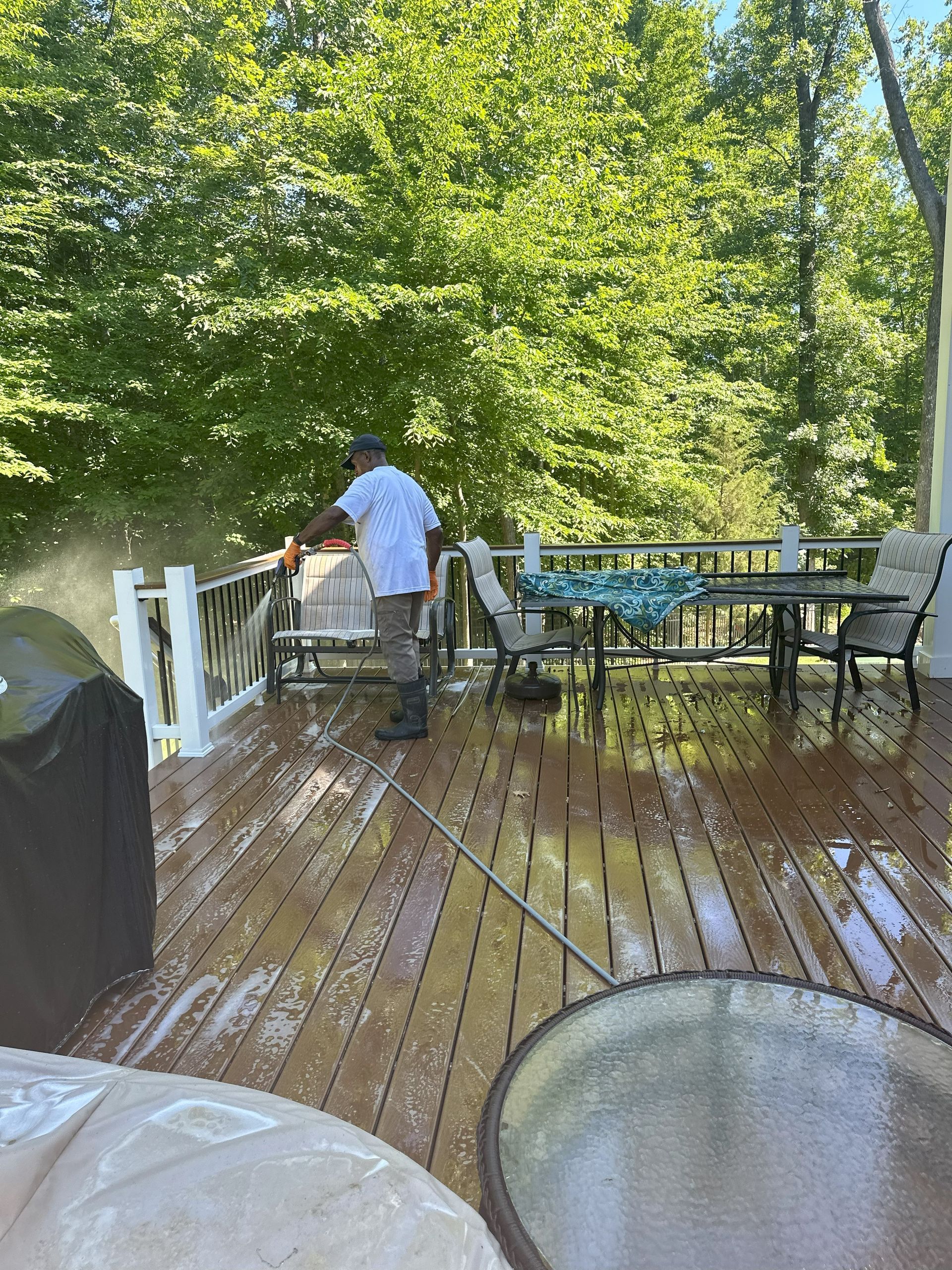 A man is cleaning a deck with a high pressure washer.
