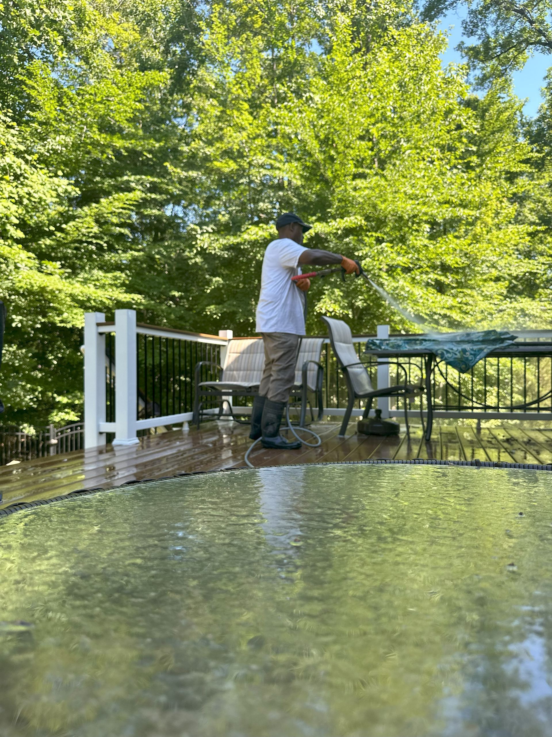 A man is cleaning a deck with a pressure washer.