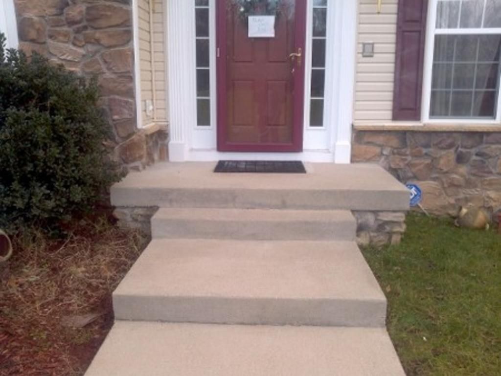 A concrete walkway leading to the front door of a house.
