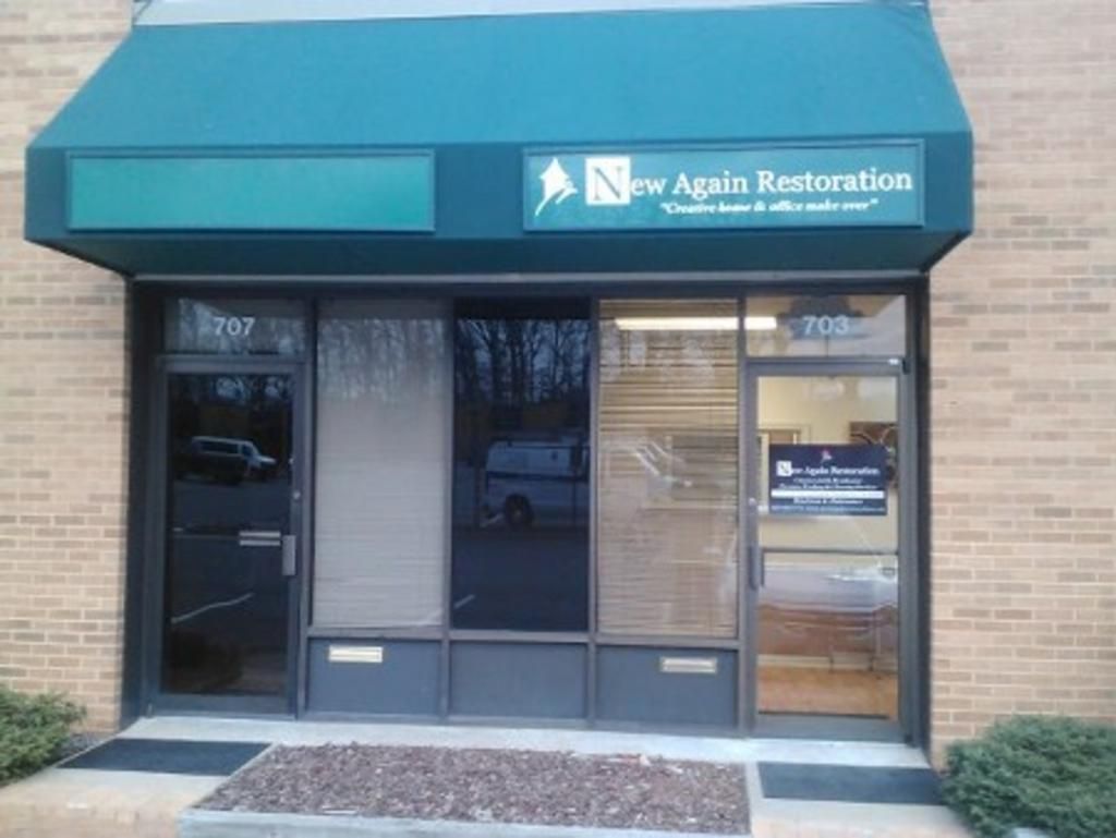 A building with a green awning that says new again restoration