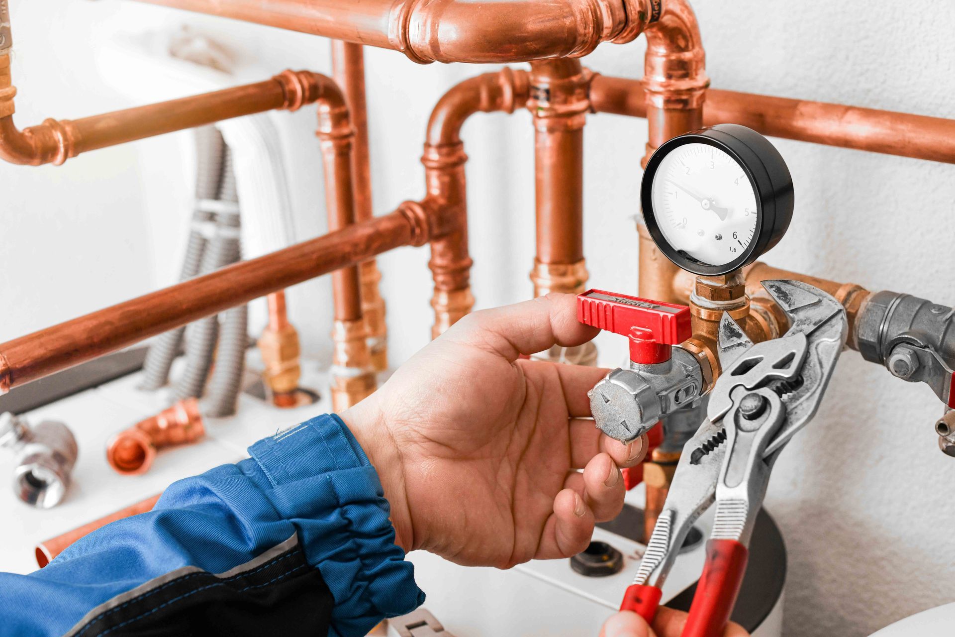 Plumber using pliers on valve with pressure gauge, copper pipes, in white setting. Plumber using pliers on valve with pressure gauge, copper pipes, in white setting.