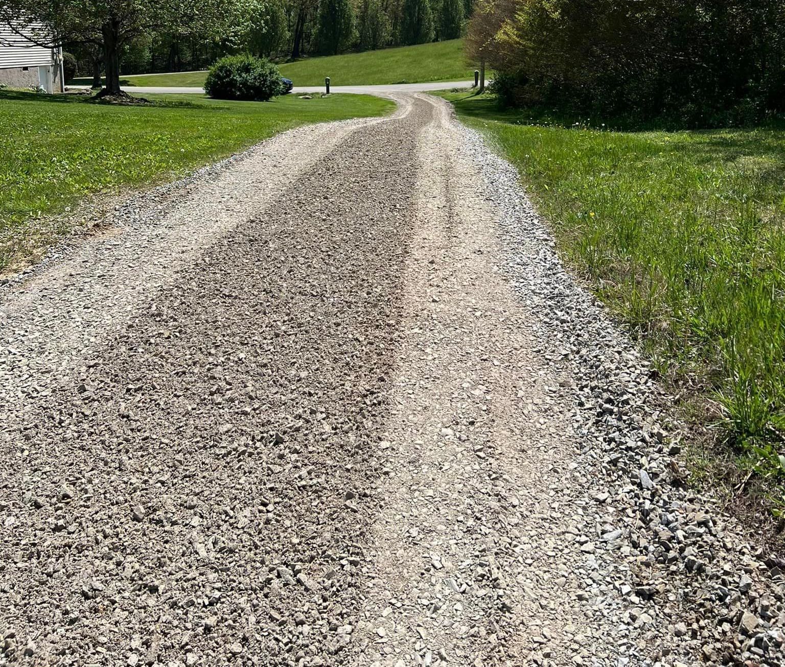 A gravel road going through a grassy field