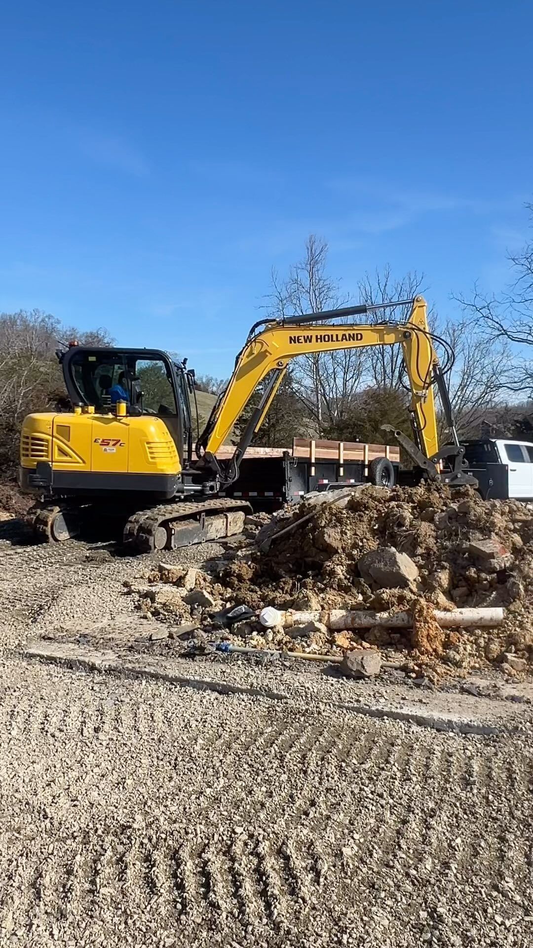Yellow excavator digging dirt on a sunny day.