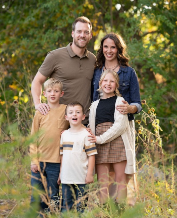 A family is posing for a picture in the woods.