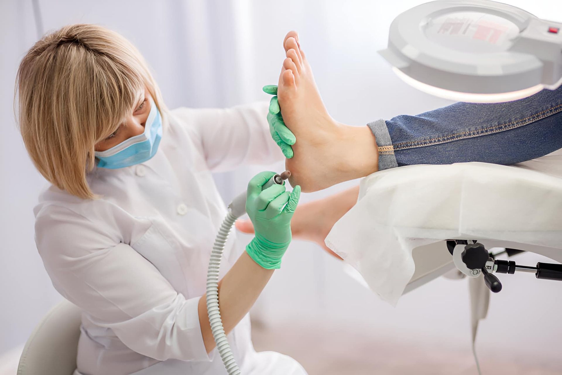 A Woman Is Cleaning A Person's Foot With A Machine — Hastings Podiatry Centre In Port Macquarie, NSW