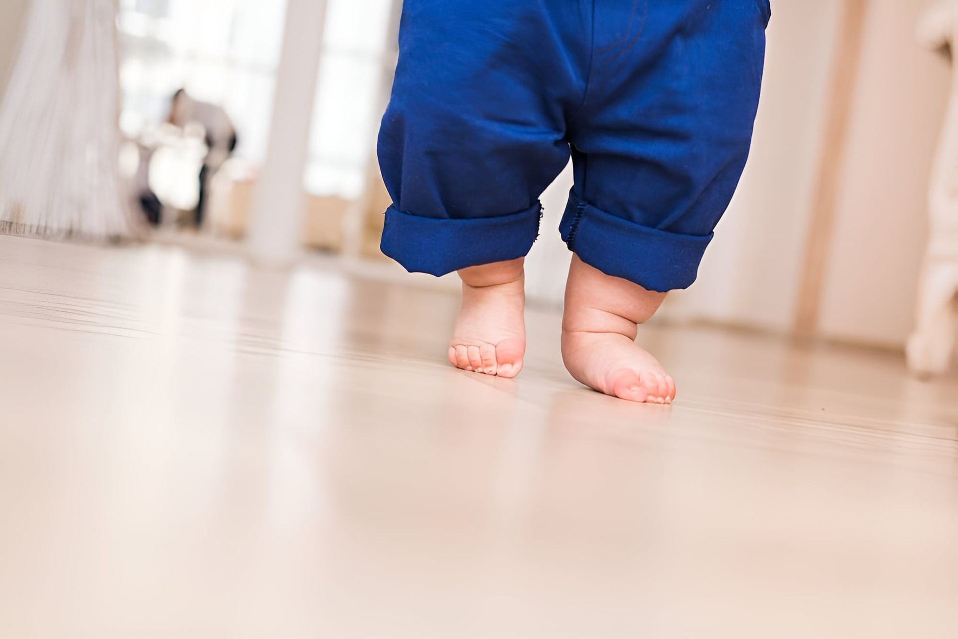 A Baby Is Walking Barefoot On A Wooden Floor — Hastings Podiatry Centre In Port Macquarie, NSW