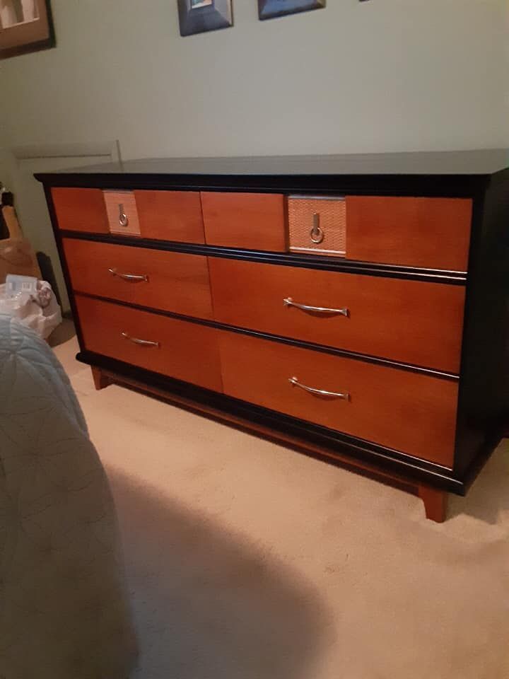 A wooden dresser is sitting in a bedroom next to a bed.