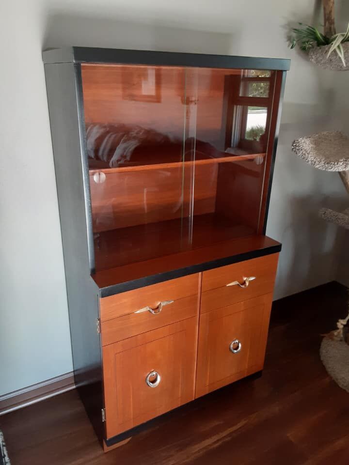 A wooden cabinet with glass doors and drawers in a living room.