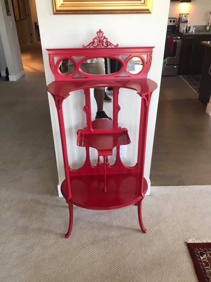 A red shelf with a mirror on top of it