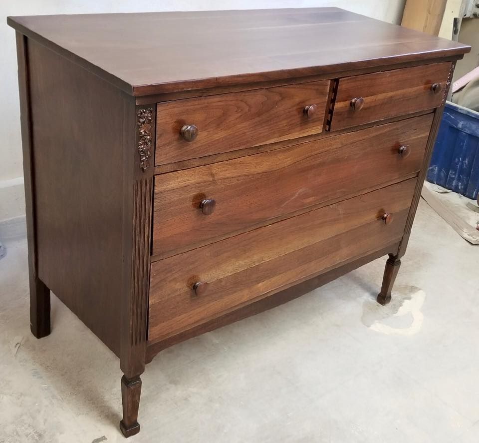 A wooden dresser with four drawers is sitting on a concrete floor.