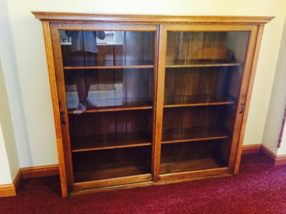 A wooden bookcase with glass doors in a room
