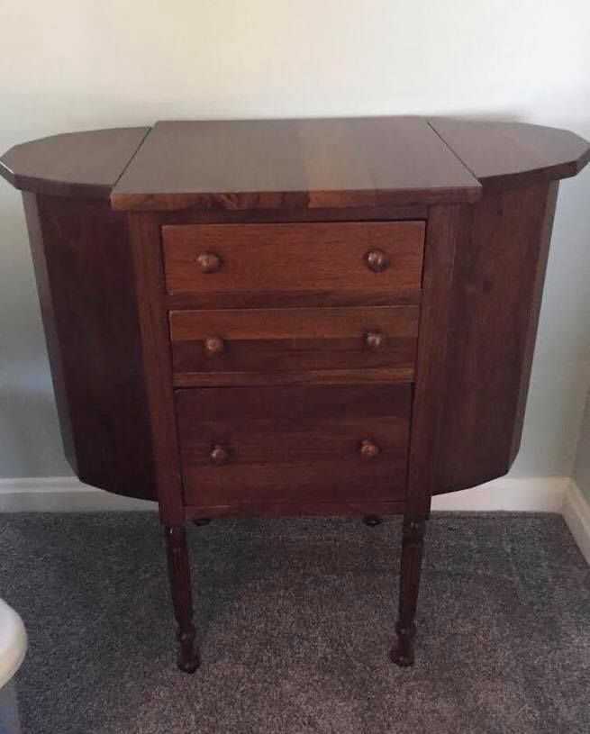 A wooden dresser with three drawers is sitting on a carpeted floor in a room.