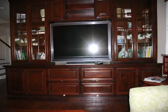 A large flat screen tv is sitting on top of a wooden entertainment center.