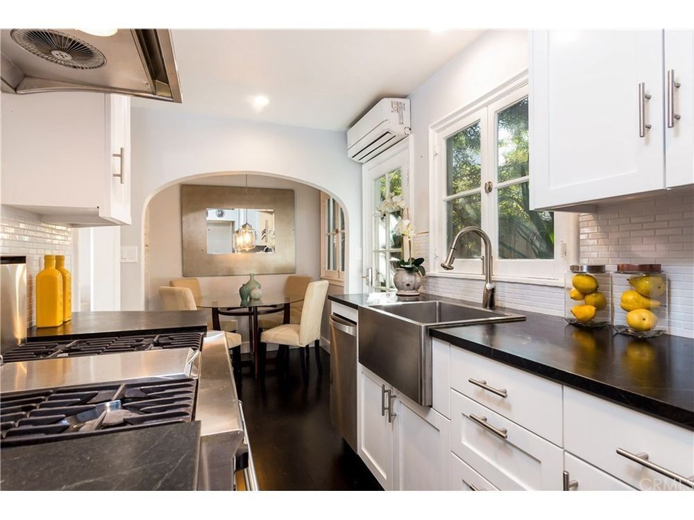 A kitchen with white cabinets and black counter tops