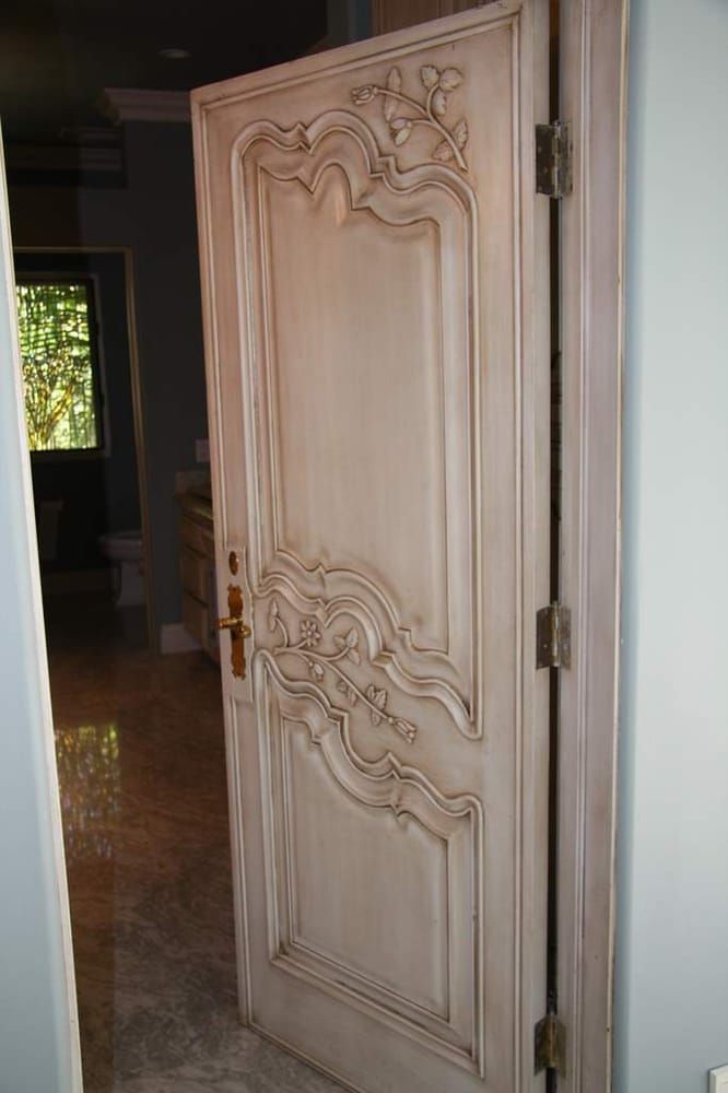 A white door with a fancy design on it is in a room.
