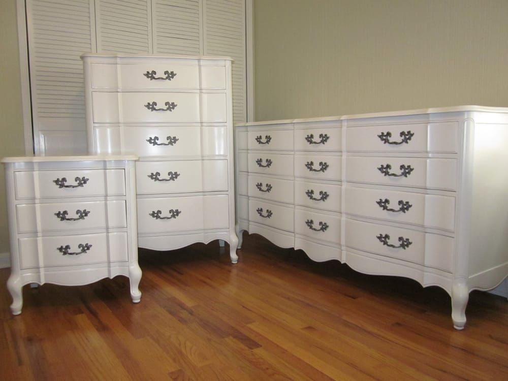 A set of white dressers with black handles on a wooden floor