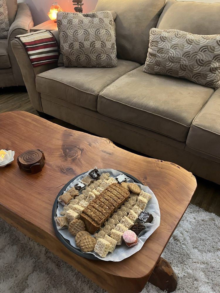 A wooden coffee table with a plate of cookies on it in front of a couch.