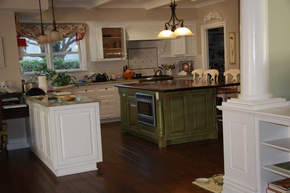 A kitchen with a green island and white cabinets