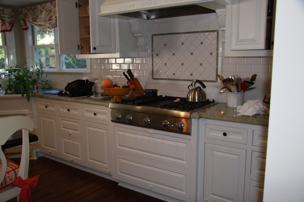 A kitchen with white cabinets and a stove top oven.